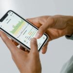 Mujer joven usando una aplicación de salud en su smartphone, con gráficos de seguimiento de actividad. Ilustra cómo las apps