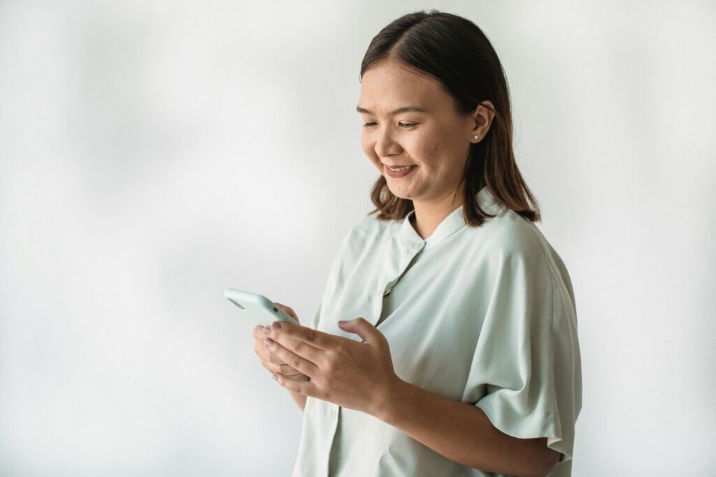 Mujer joven sonriendo mientras consulta una aplicación de salud con inteligencia artificial en su smartphone, mostrando gráfi