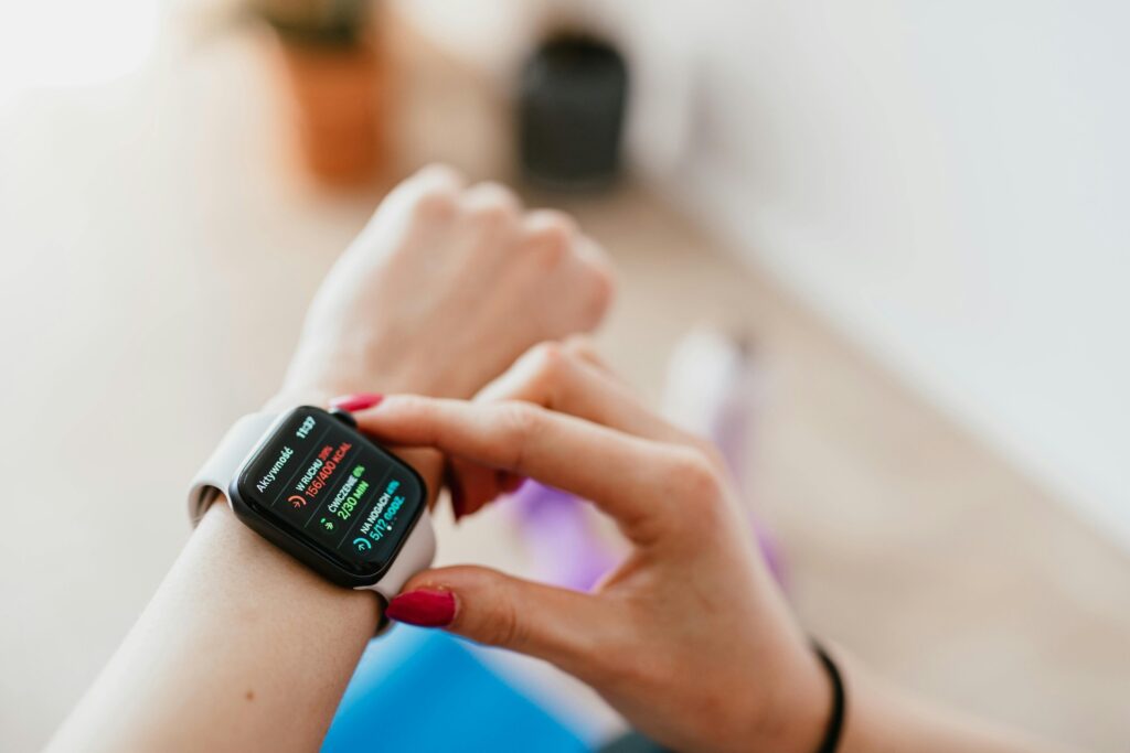 Una mujer joven con una sonrisa serena consulta una aplicación de salud en su smartwatch mientras realiza ejercicio suave al