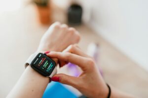 Una mujer joven con una sonrisa serena consulta una aplicación de salud en su smartwatch mientras realiza ejercicio suave al
