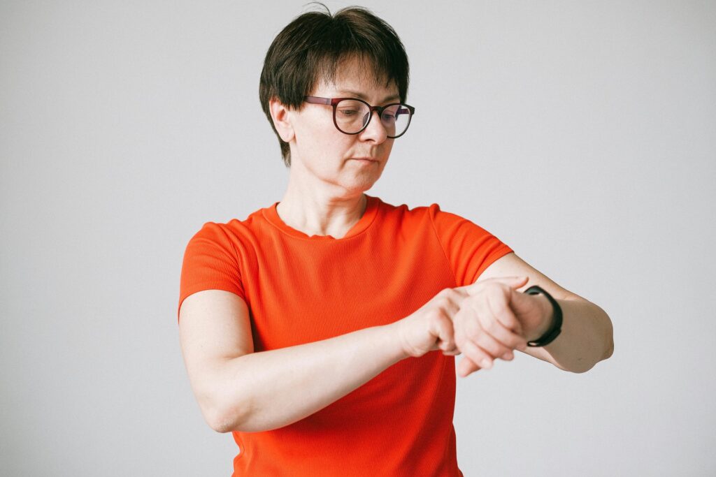 Una mujer joven mira atentamente la pantalla de su smartwatch, que muestra gráficos de datos de salud analizados por IA, con