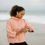 Mujer sonriente y activa, de unos 30 años, observando gráficos detallados de datos de salud en su smartwatch al aire libre, r