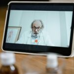 Médico sonriente interactuando con un paciente a través de una videollamada en una tablet, ilustrando la telemedicina moderna