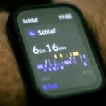 Una persona activa usando un smartwatch mostrando gráficos de datos de salud impulsados por IA, con interfaz digital. Enfatiz