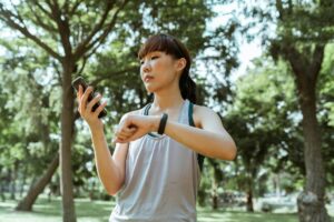 Una mujer sonriente de mediana edad interactuando con una aplicación de salud en su smartphone, que muestra gráficos de activ