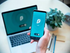 Una persona joven mirando la pantalla de un smartphone con iconos de candado y escudo superpuestos, simbolizando la protecció