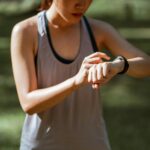 Una mujer sonriente de mediana edad revisando datos de salud personalizada en su smartwatch, con gráficos digitales flotando