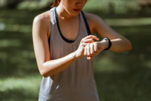Una mujer sonriente de mediana edad revisando datos de salud personalizada en su smartwatch, con gráficos digitales flotando