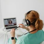 Una mujer sonriente consulta los datos de su smartwatch de salud mientras un médico, usando una tablet, revisa la información