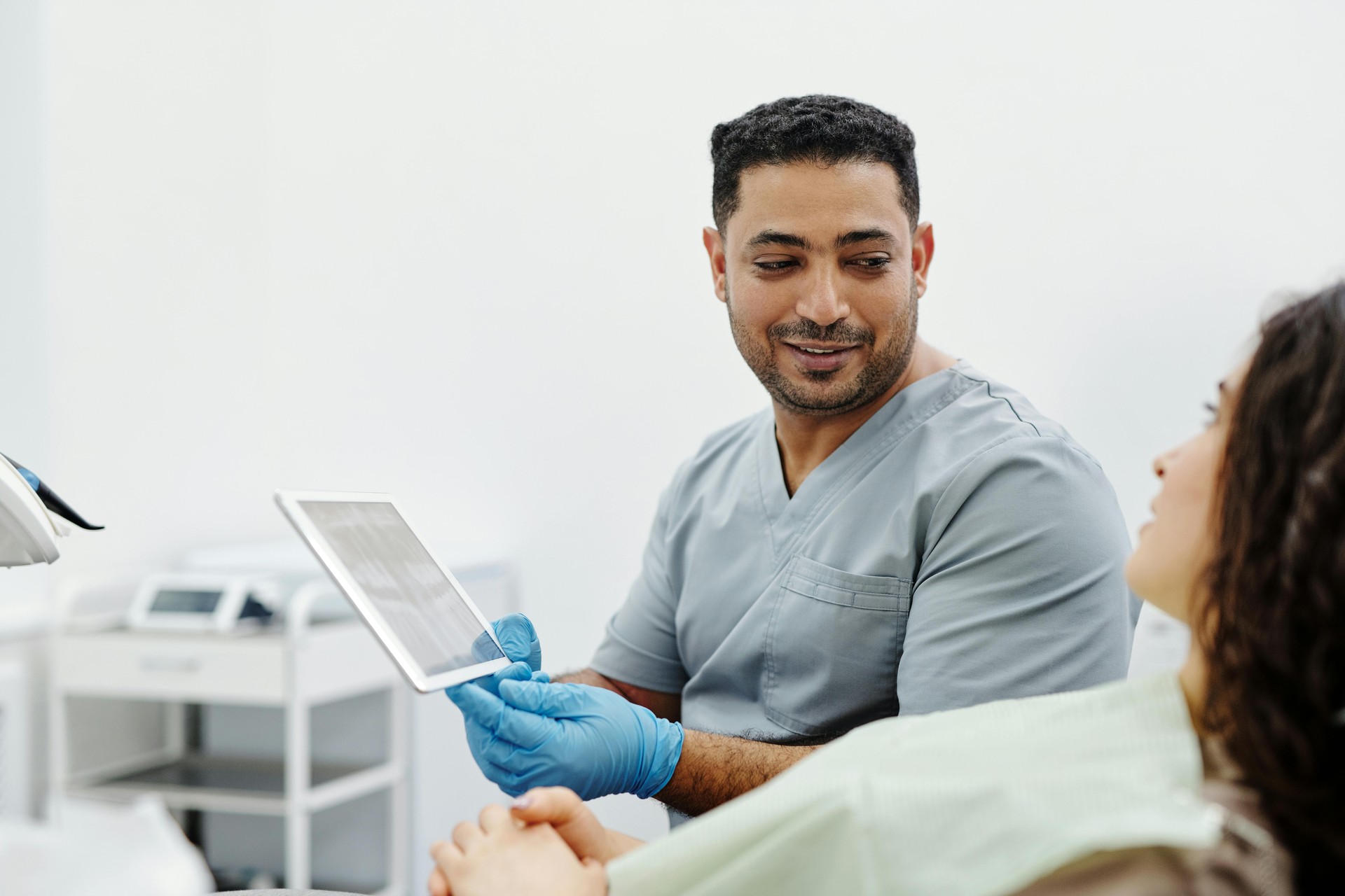 Un médico profesional explica información de salud a un paciente utilizando una tablet que muestra datos y gráficos generados