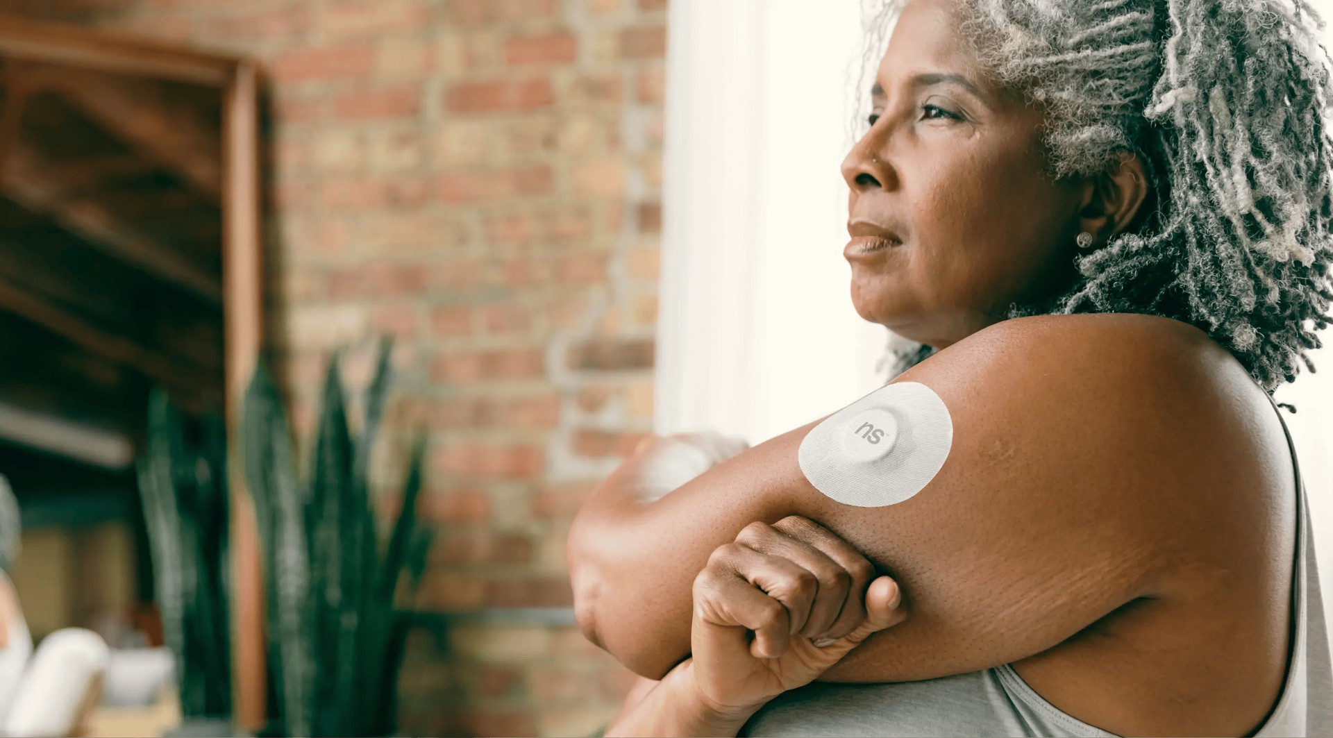 Parche médico inteligente en el brazo de un paciente, monitoreando constantes vitales para la gestión de su condición crónica