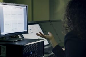 Joven revisando datos de salud en una interfaz futurista o pantalla táctil, con un smartwatch visible, representando la preve