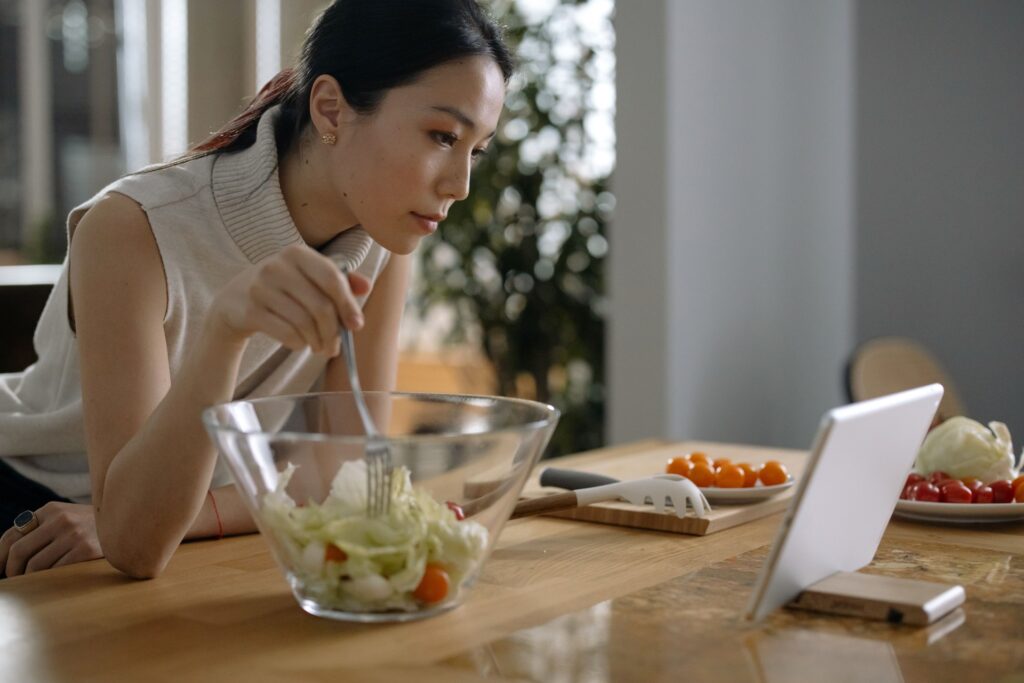 Mujer sonriente usando una tablet para consultar una app de nutrición personalizada, con frutas y verduras frescas sobre la m